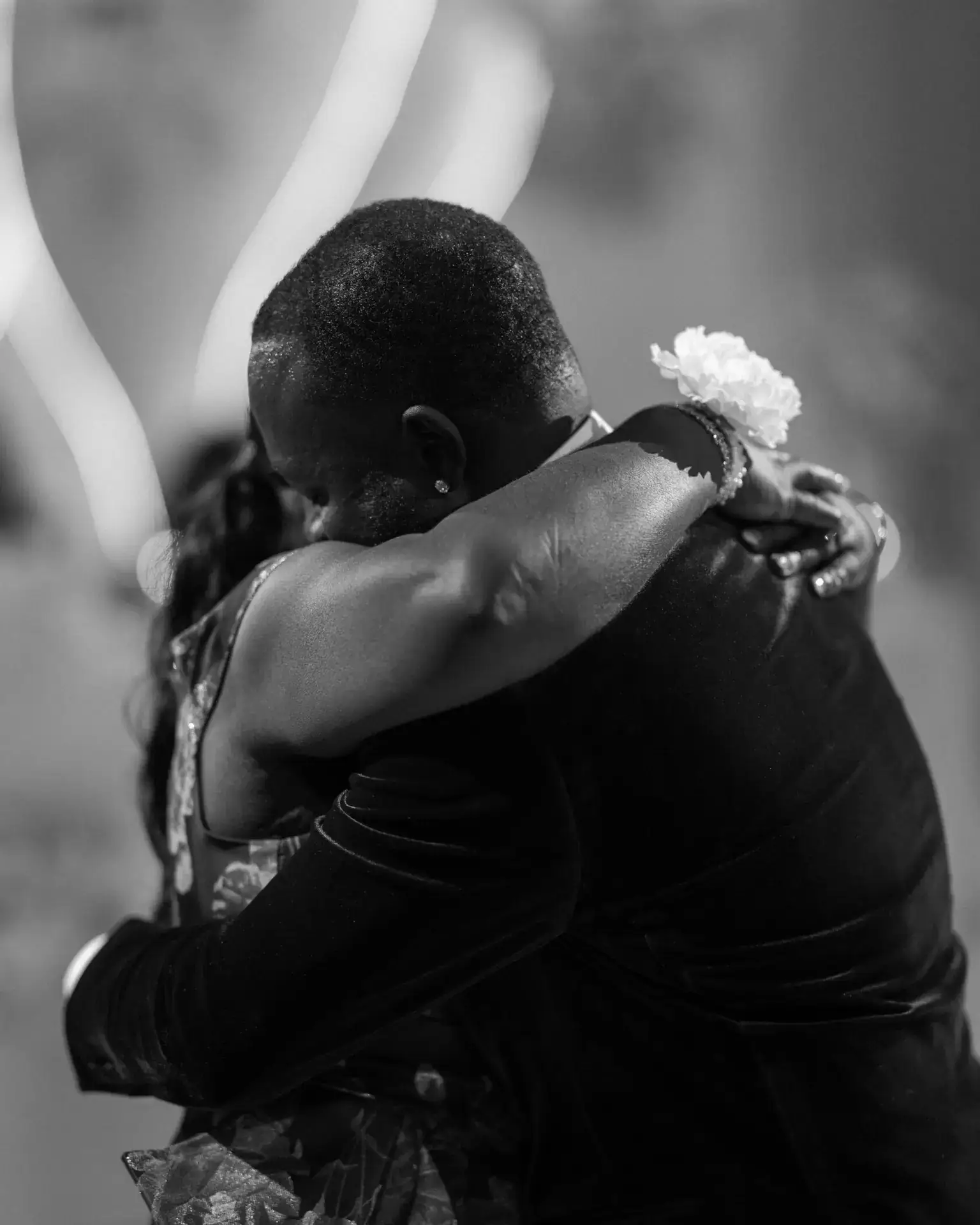 Man in velvet tuxedo tightly embracing a woman wearing a wrist corsage