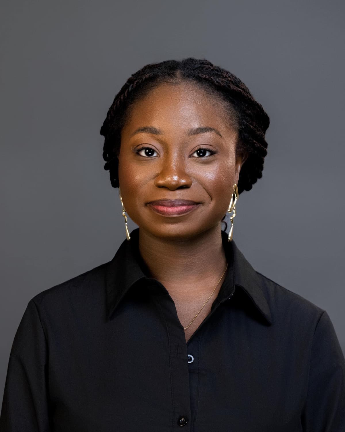 Corporate headshot in a black button-up shirt on a gray studio backdrop